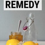 Lemons on lemon squeezer with jar of honey and glass bottle