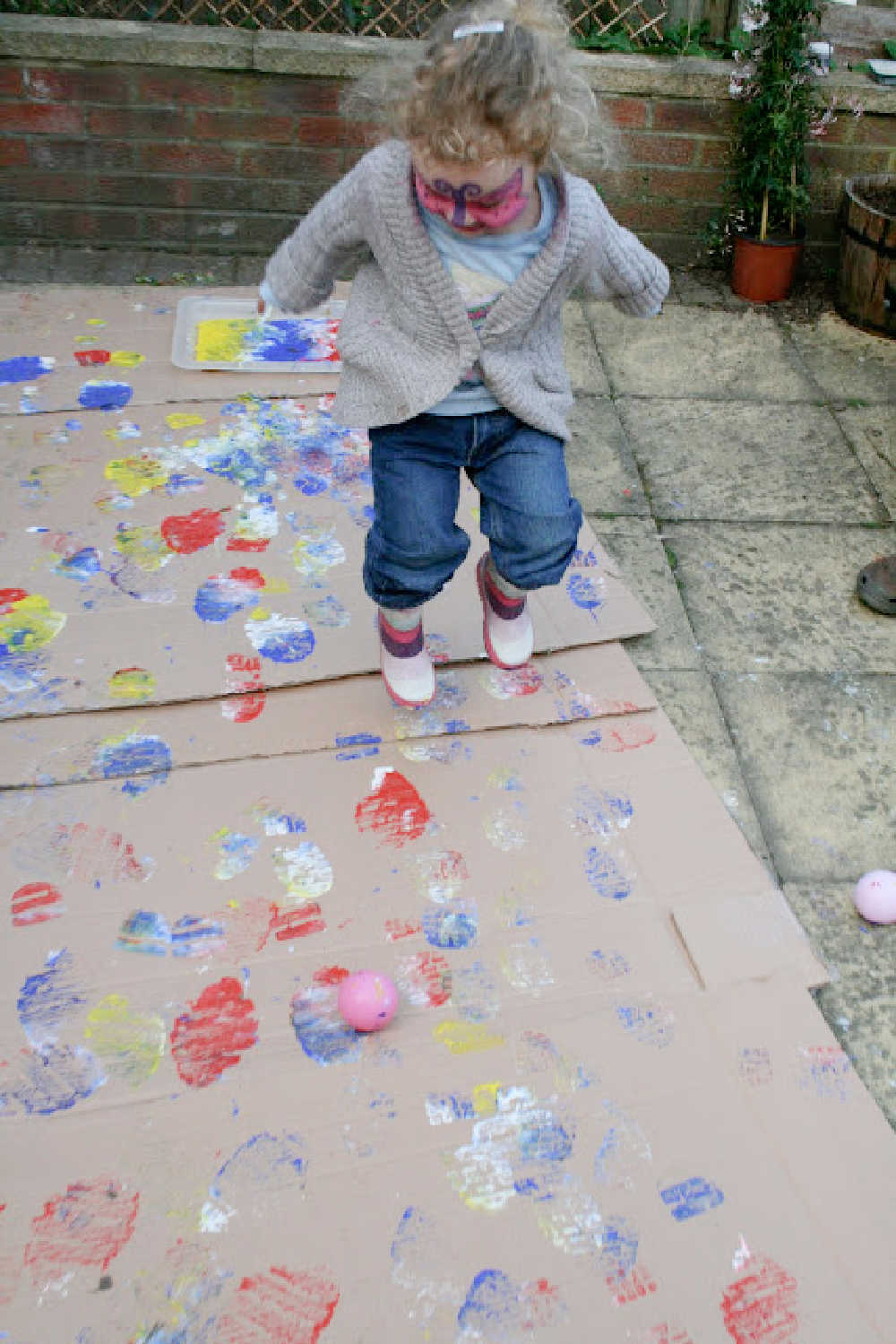 Child painting outdoors using rain boots