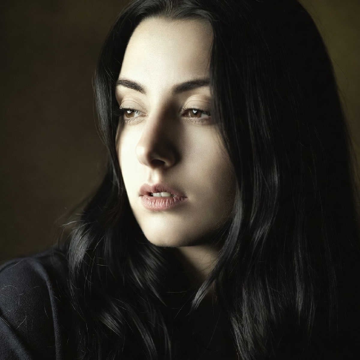 Young woman with long dark hair looking sad