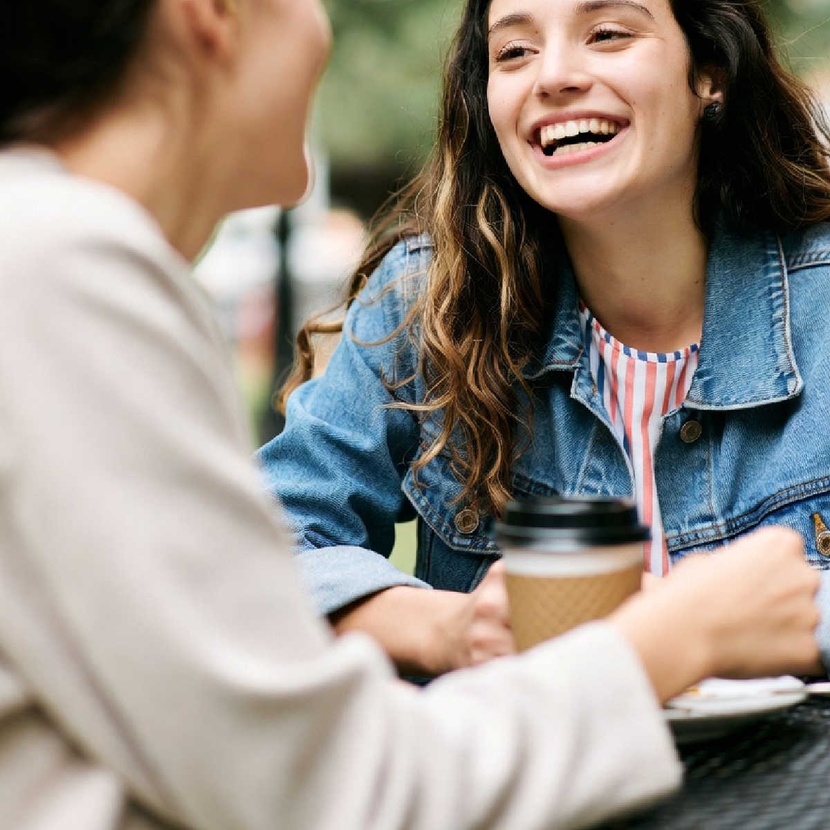 Young smiling women talking over coffee