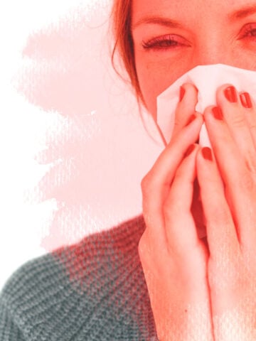 Young woman blowing nose with tissue