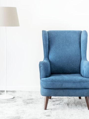 A blue arm chair next to a floor lamp
