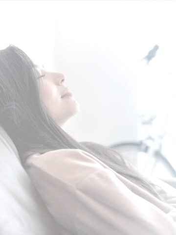 Young woman lying back on bed resting