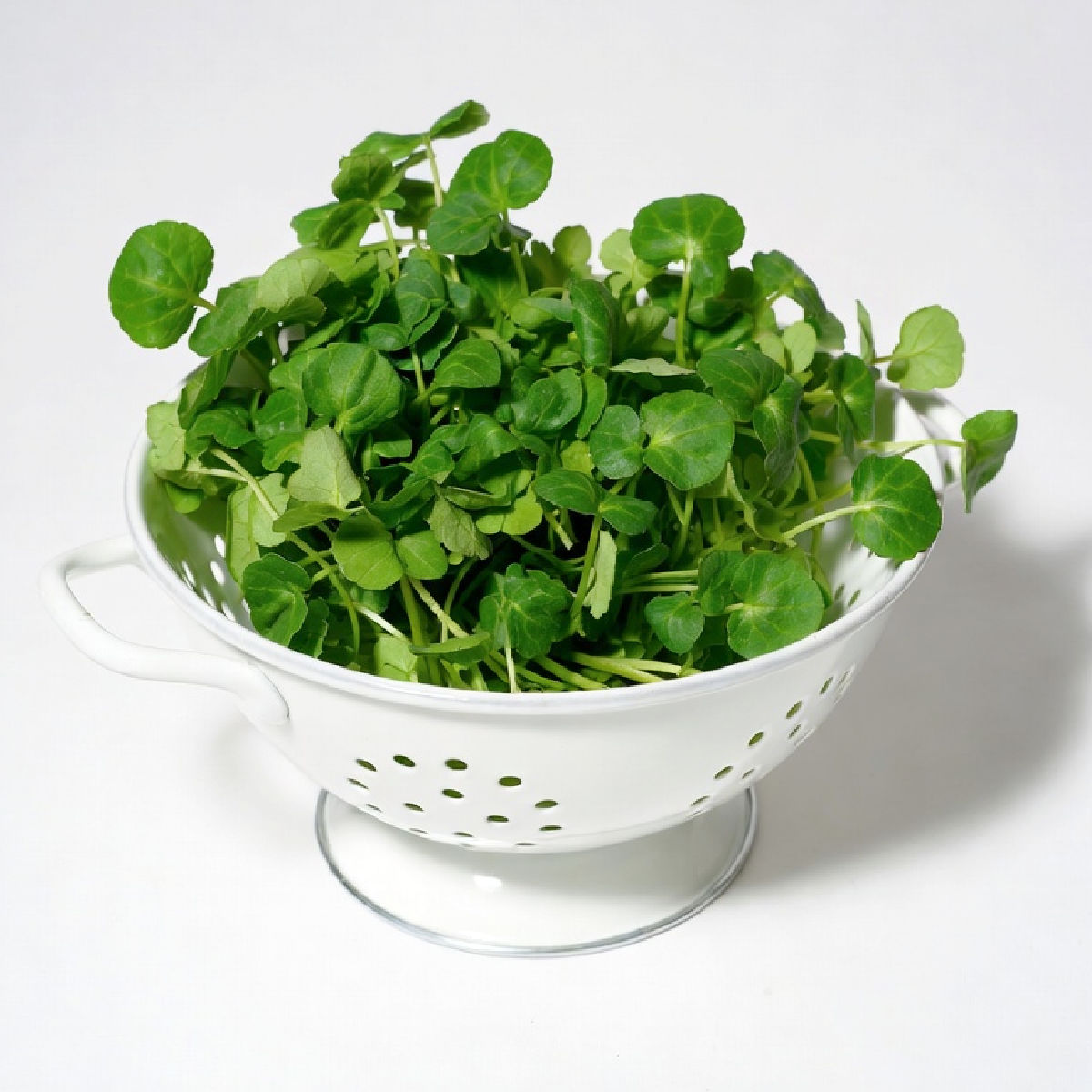 A white colander containing water cress