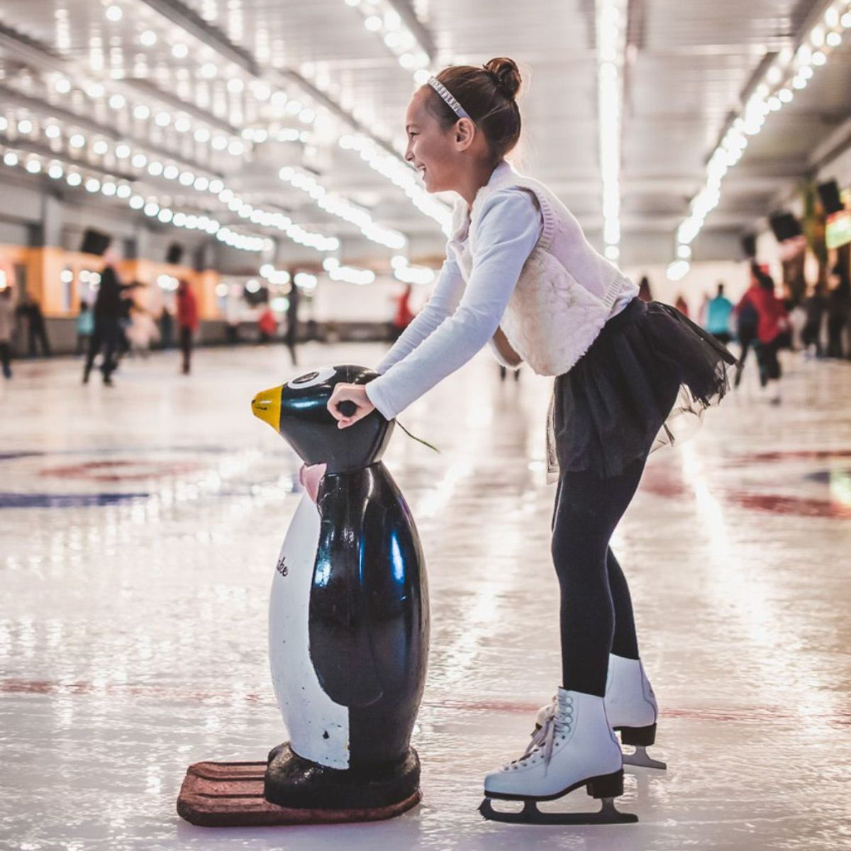 Girl ice skating with penguin support